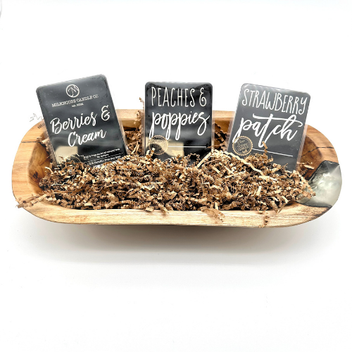 Three candle samples with labels in a wooden bowl on a white background