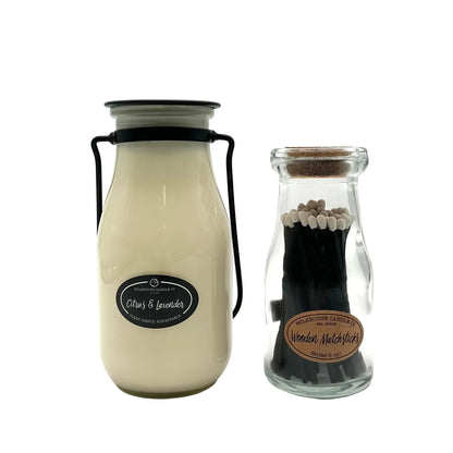 Glass bottle with black lid and white label next to a smaller glass bottle with wooden matches on a white background