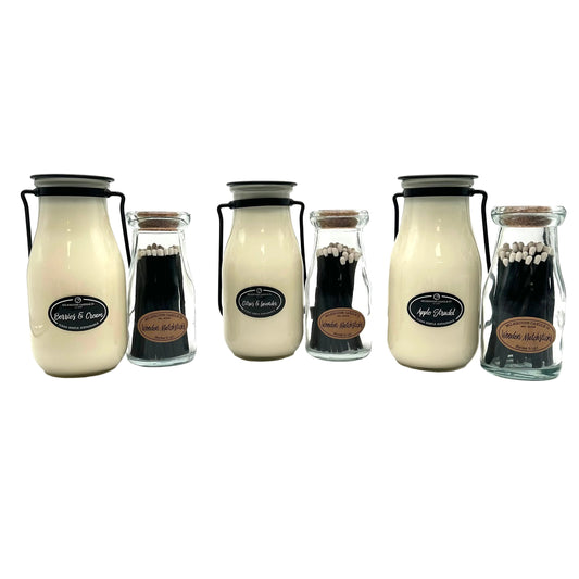 Set of milk bottle-shaped candles with labels on a white background