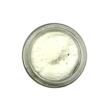 Small glass jar filled with a white creamy substance on a white background