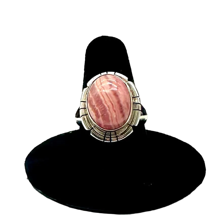 Ring with pink stone and silver band on a black stand against a white background